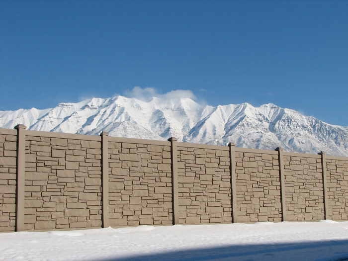 A simulated stone fence surrounded by snow with a mountain in the background