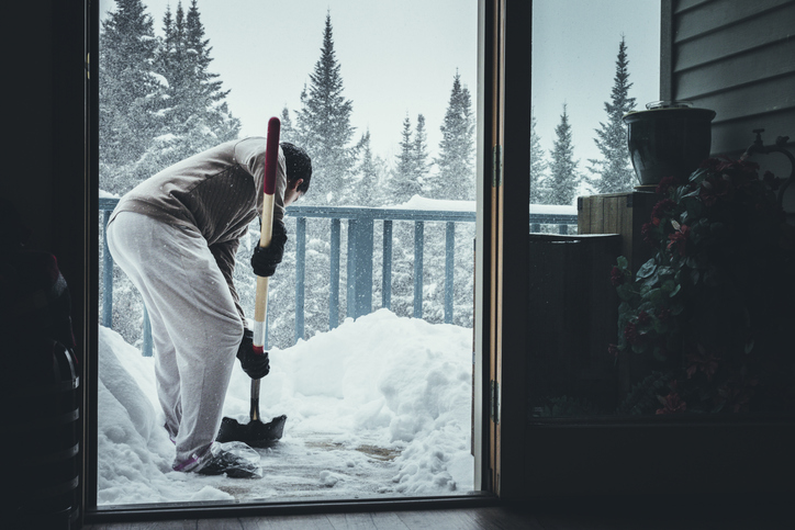 Person shoveling snow off their deck with a plastic shovel