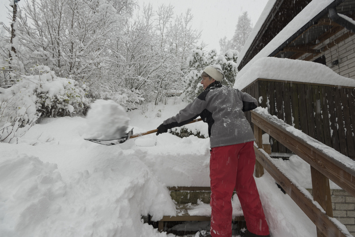Woman removing snow from the stairs of her deck