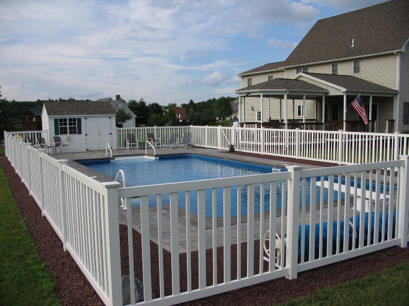 A white seneca pool fence around a private inground pool in the back yard