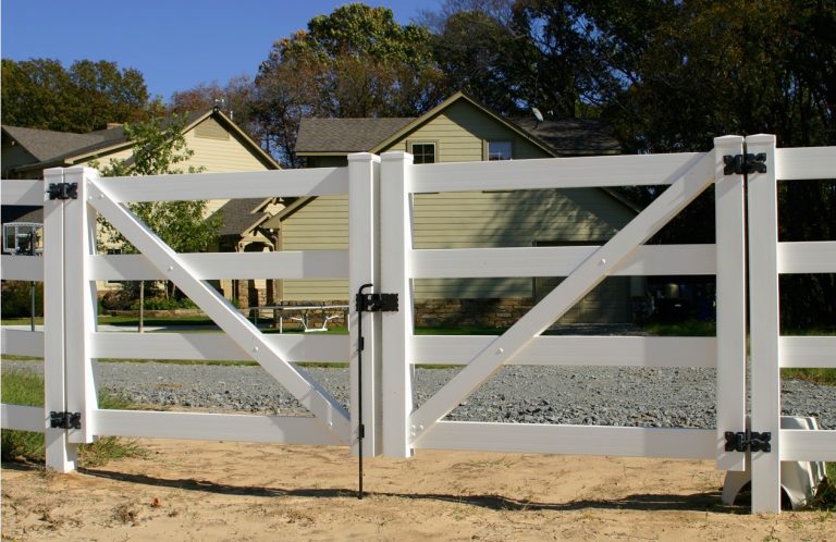 White vinyl fence gate with a drop rod lock on a horse ranch